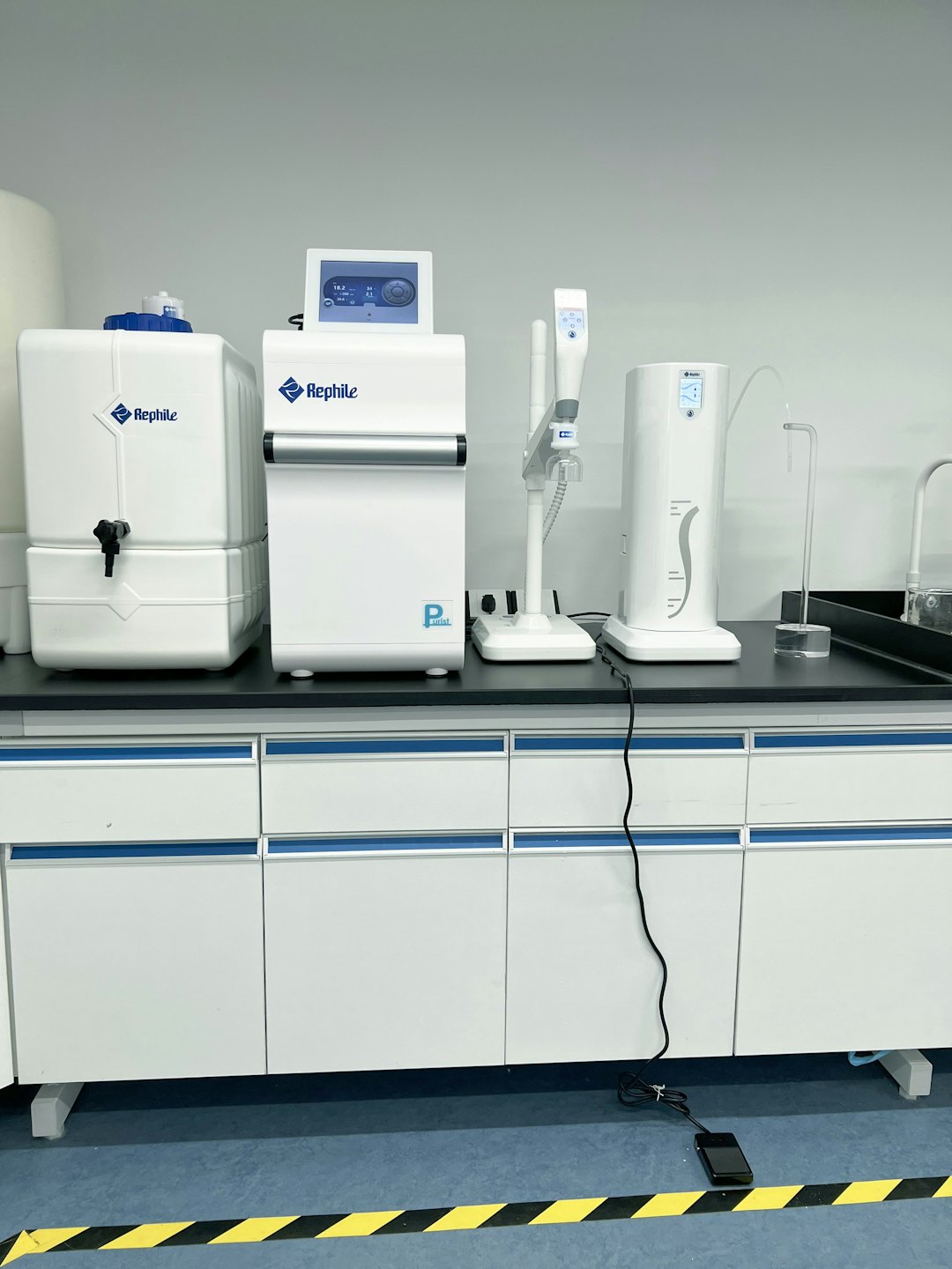 Apparecchiature di laboratorio per la purificazione dell'acqua su un banco da lavoro nero.