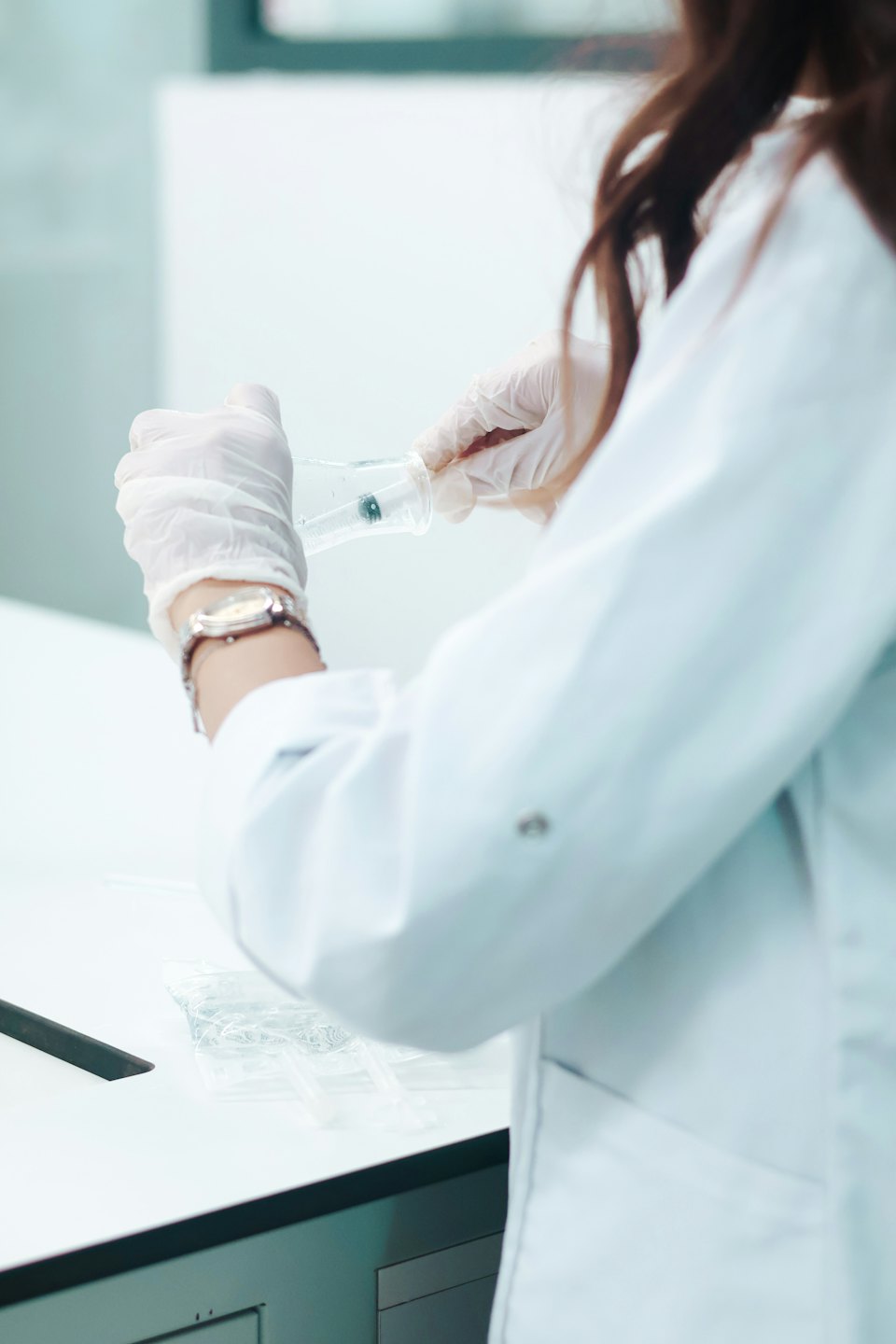 Scienziato in camice da laboratorio che lavora con becher e siringa.